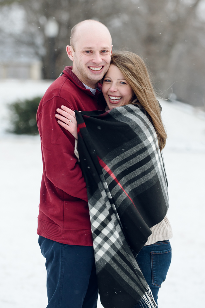 an engaged couple snuggling under a blanket in Mellon Park in Pittsburgh, Pennsylvania