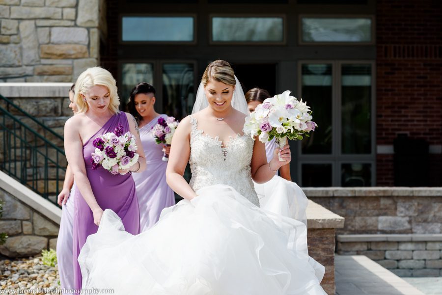<alt> bridesmaid holds bride's dress as they walk at Southpointe Country Club in Southpointe, Pennsylvania</alt>