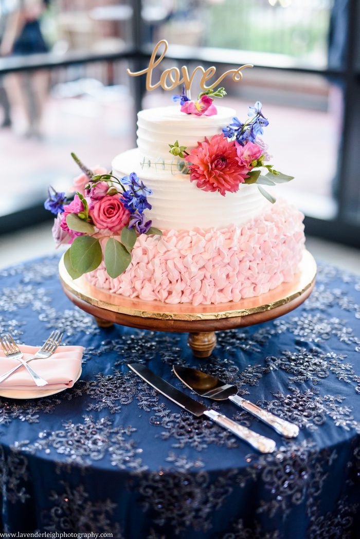 <alt> wedding cake accented with pink flowers at the Duquesne Power Center in Pittsburgh, Pennsylvania</alt>