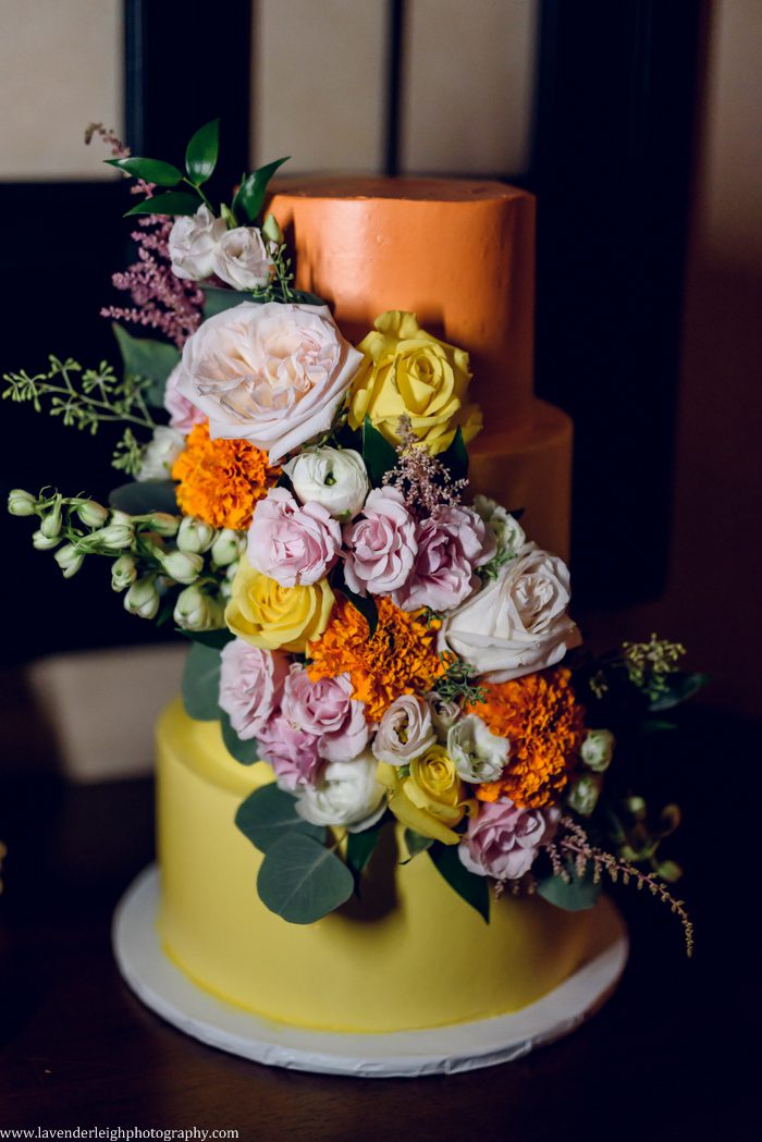 <alt>an orange and yellow wedding cake with vibrant flowers at Bella Sera in Canonsburg, Pennsylvania</alt>