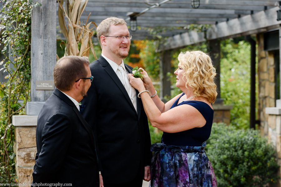 Mother of Groom Puts Boutonniere on Groom at the Pittsburgh Botanical Garden