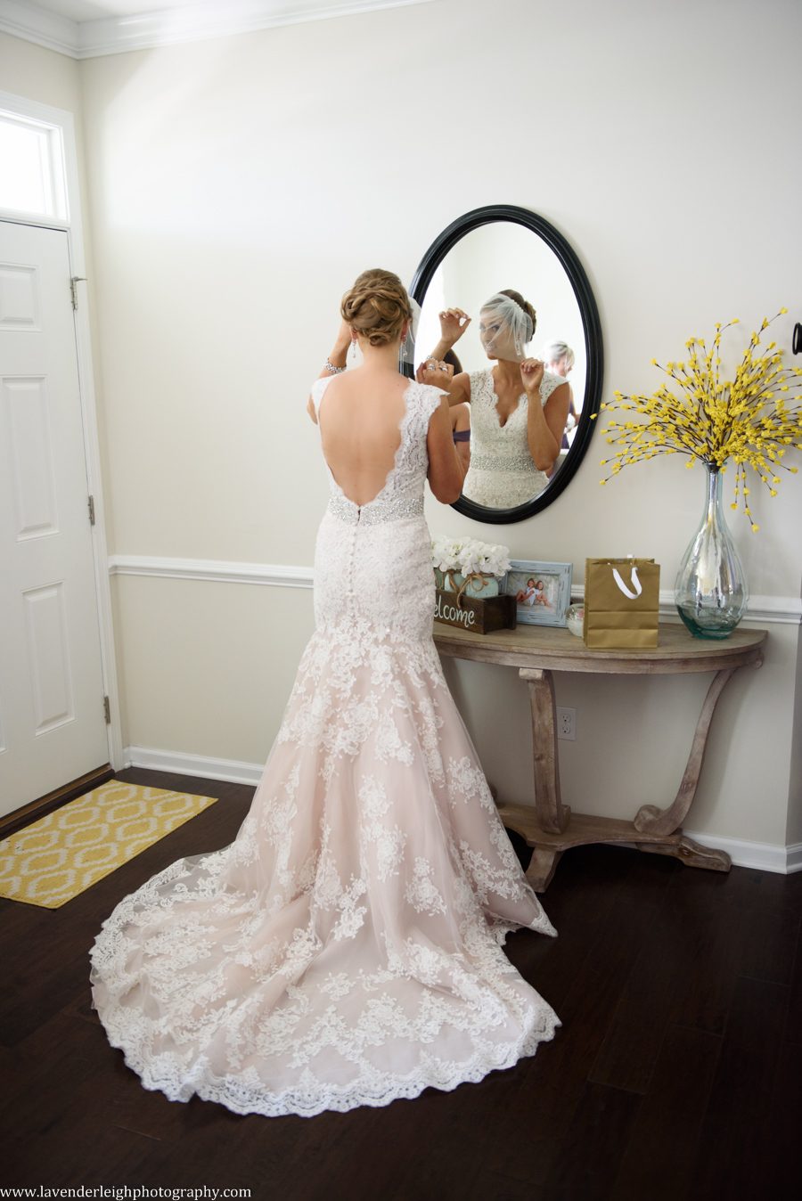 A bride pins and straightens her bird cage veil in the mirror