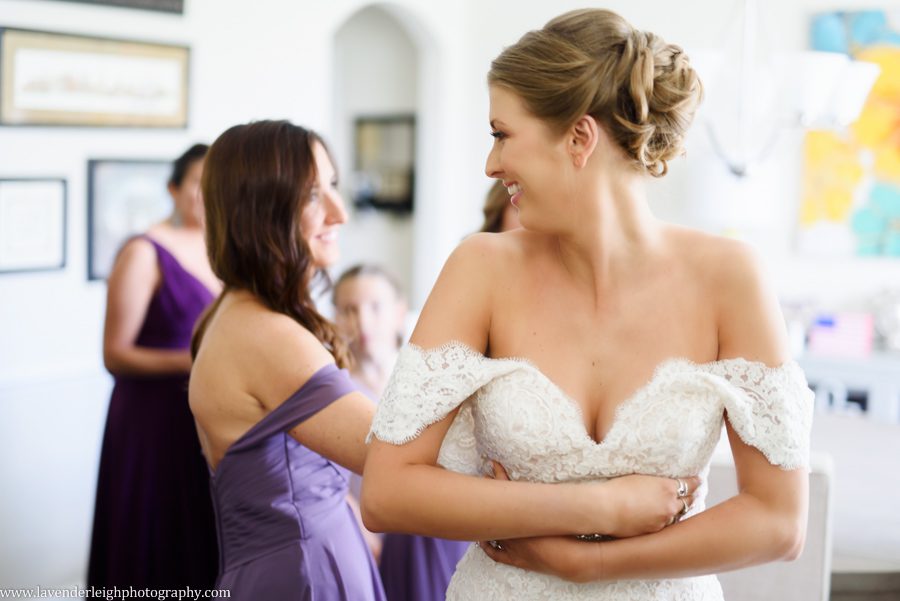The maid of honor helps to button the bride's wedding dress