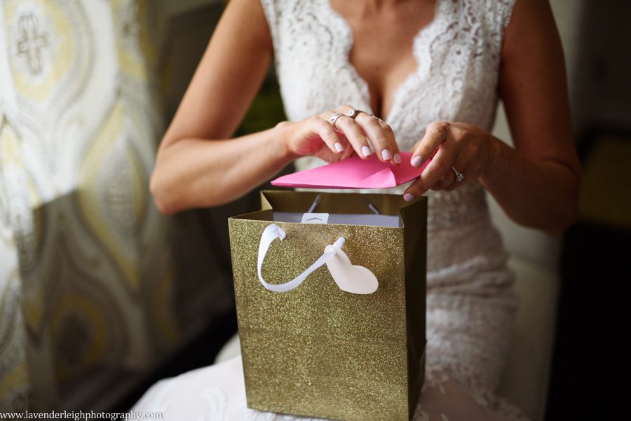 A bride opens a card and a gift from the groom