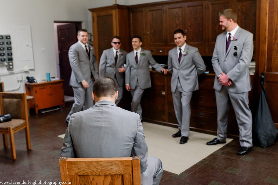 The groomsmen watch the groom open his gift from the bride