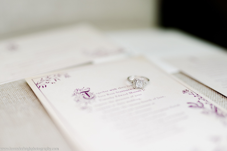 An engagement ring sitting on top of a purple font wedding invitation by Lavender Leigh Photography