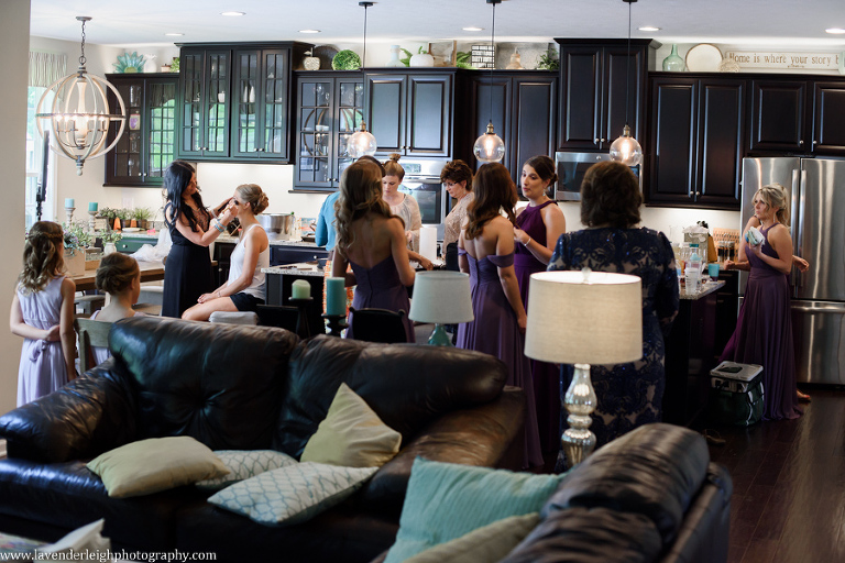 The bride has her makeup completed while bridesmaids fix their hair