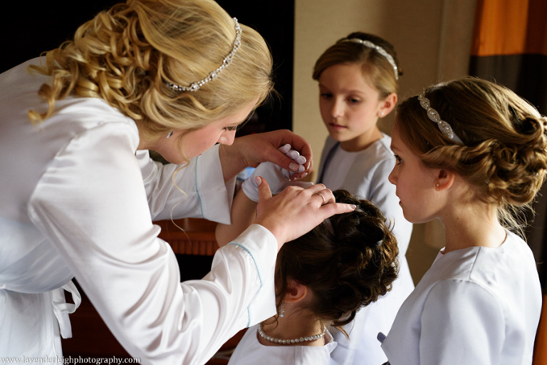 A bride helping her flower girl put on her tiara