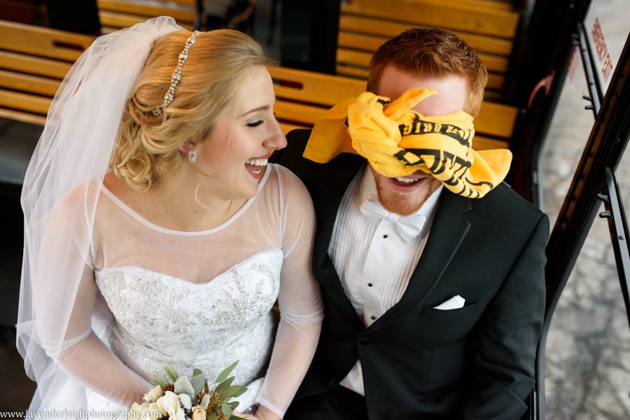 A bride and groom on the trolley, groom is wearing a terrible towel as a blindfold
