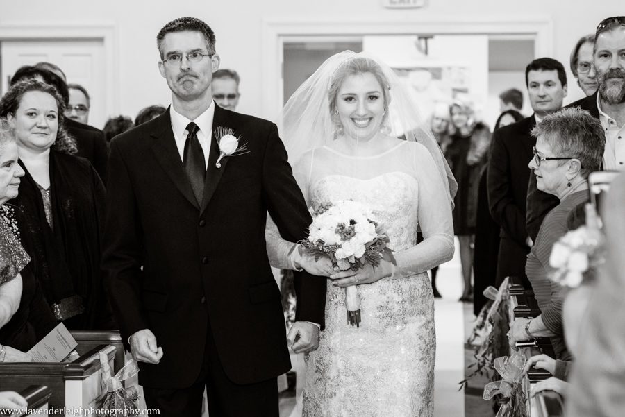 A bride smiles at her groom as she walks down the aisle