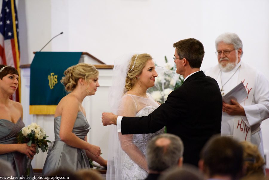 A bride's father lifting her blusher before he gives her away