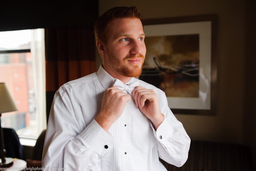 A groom putting on his tie on his wedding day