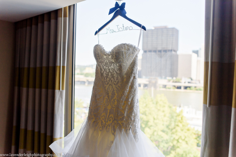 A lace and ruffle wedding dress hanging in a window.