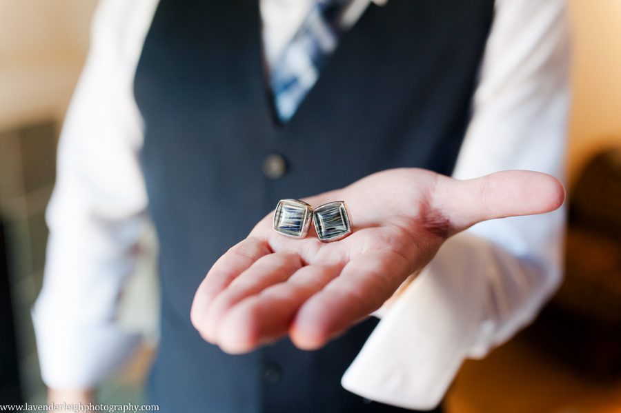 The groom holds his navy swirl cuff links