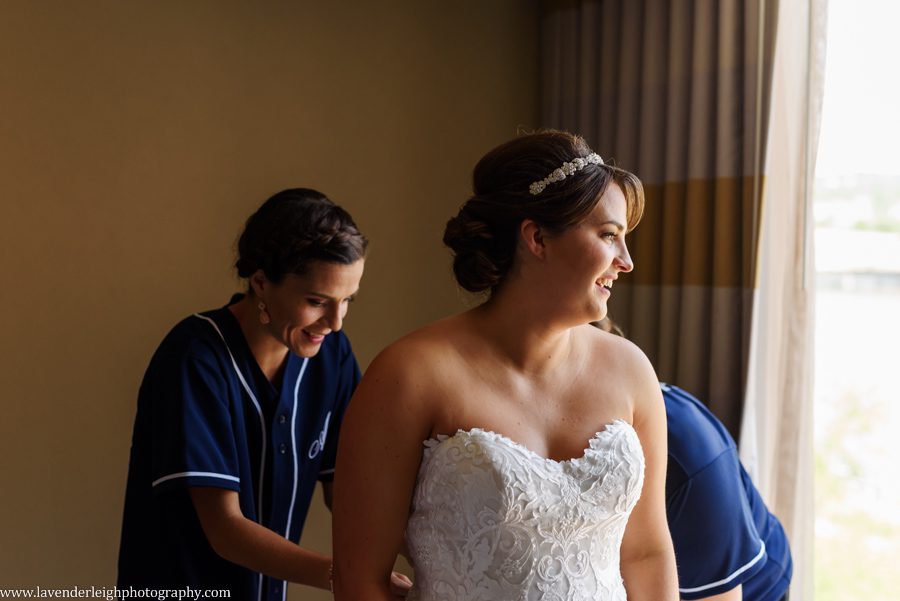 The bridesmaids are buttoning the bride's wedding dress at Sheraton Station Sqaure.