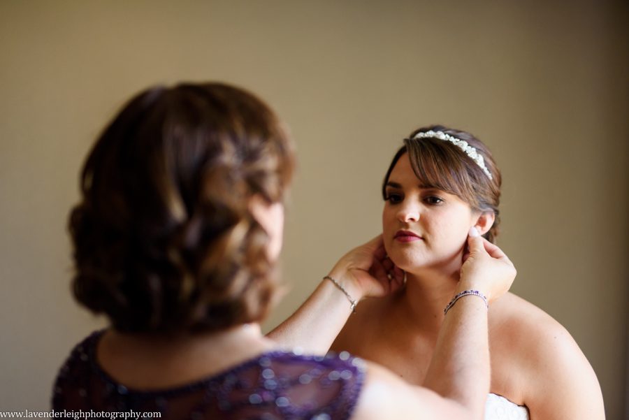The mother of the bride helps the bride to fasten her earrings at the Sheraton Station Square in Pittsburgh, Pennsylvania.