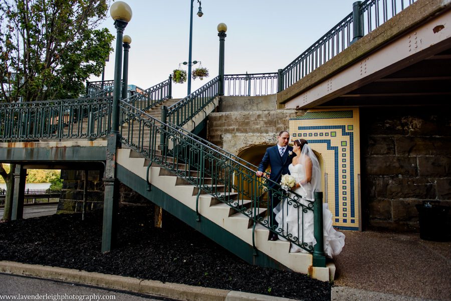 The bride and groom take a picture at the stairway outside of The Grand Concourse in Pittsburgh, Pennsylvania