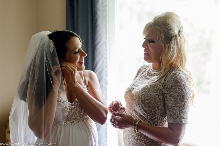 The bride puts her wedding earrings on as her mother helps