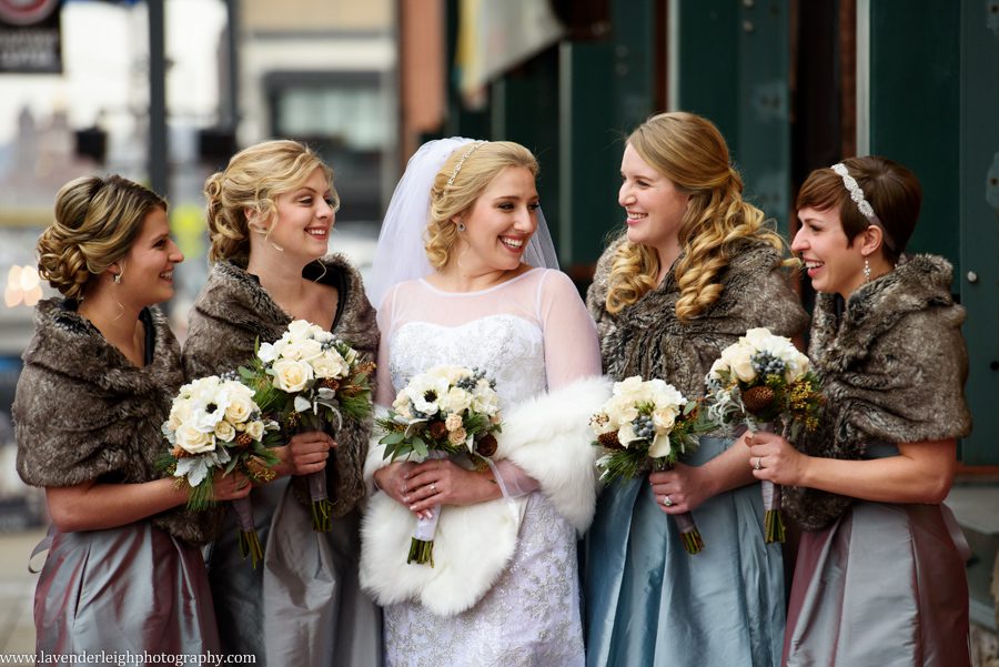 A winter white bride laughing and smiling with her bridesmaids in ice blue dresses