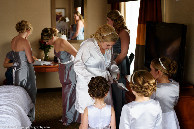 A bride helping her bridesmaids and flower girls put on their dresses