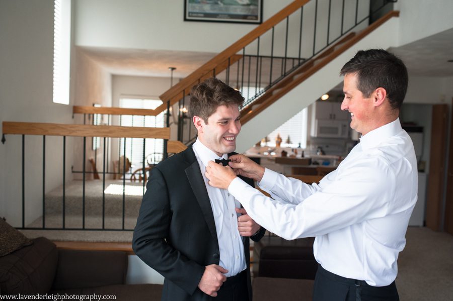 The Best Man is helping the groom tie his bowtie