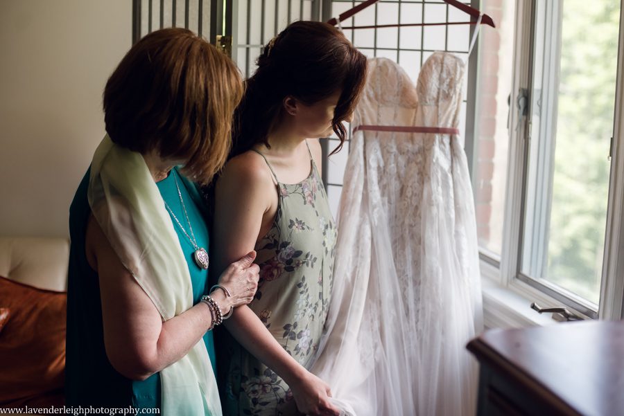 <alt>mother and daughter looking at bride's wedding dress</alt>