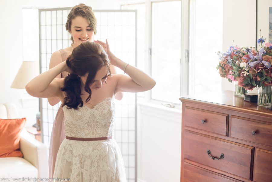 <alt>maid of honor putting necklace on bride</alt>