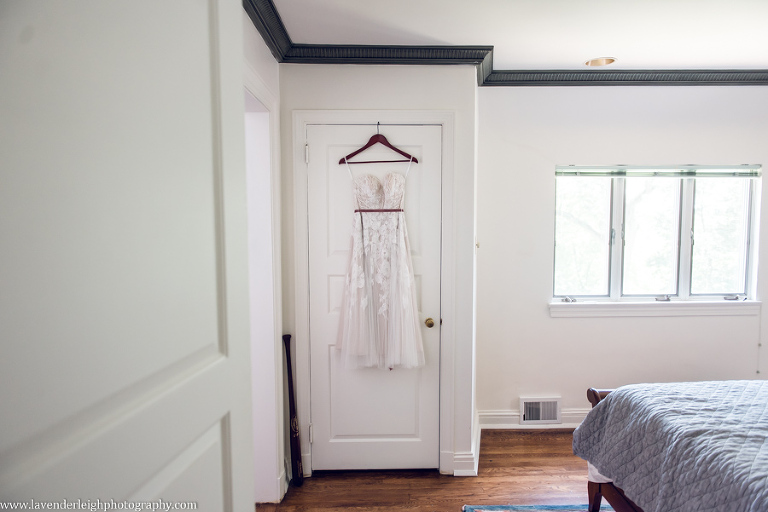 <alt>lace Bhldn wedding dress hanging on a door</alt>